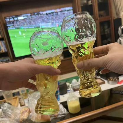 Crystal trophy glasses held up, one with amber beer and one with green-tinted drink