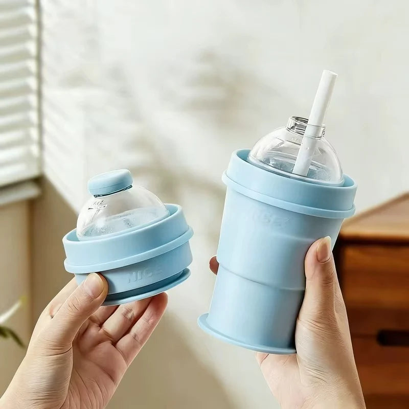 Blue collapsible ice cup with clear lid and straw, held in hands
